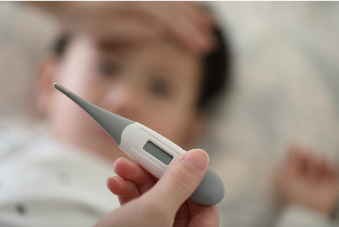 Orang tua mengukur suhu tubuh anak dengan termometer